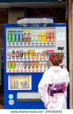 KYOTO, JAPAN - DECEMBER 31, 2014: Young woman wearing kimono using vending machine. Japan has the highest number of vending machines per capital, with about one machine for every twenty-three people.
