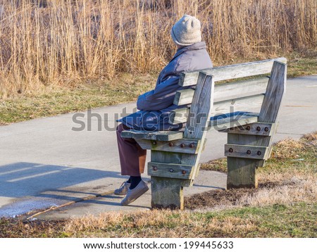 Aging old woman sitting alone park bench silhouette