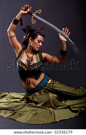 Bellydancer, seated on floor and holding up sword