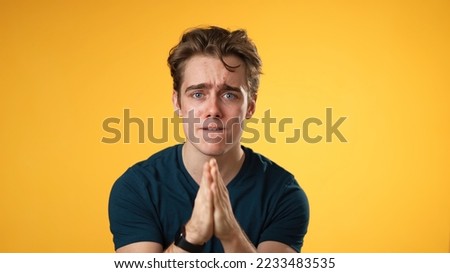 Young worried pleading man 20s hold hands folded in prayer begging about something making wish keep fingers crossed isolated on yellow background studio. People lifestyle concept  Stockfoto © 
