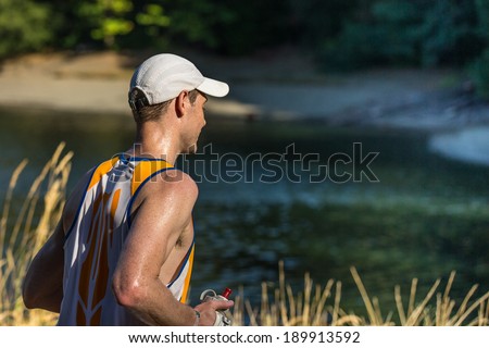 Running Man with Copy Space - man running around a lake during an endurance trail run with copy space on the right.