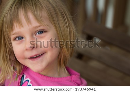 Smiling Girl - young girl on porch swing looking at the camera.  Smiling /  happy expression.