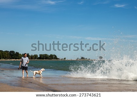 CHICAGO ILLINOIS - September 6, 2014: Man walking his dog at Chicago lake shore north of Oak Street Beach.  Chicago is a large city but its lake shore offers numerous recreational opportunities.
