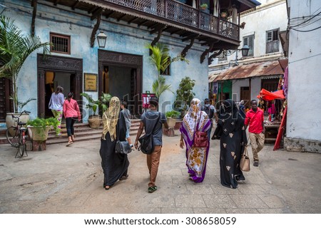 STONE TOWN, ZANZIBAR - AUGUST 15, 2014: Local people on a typical narrow street in Stone Town. Stone Town is the old part of Zanzibar City, the capital of Zanzibar, Tanzania.