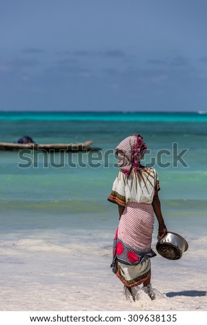 Local woman picking water from the sea in Zanzibar, Tanzania, Africa