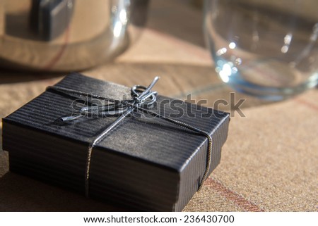 small black jewelry gift box with a silver bow in morning sunlight