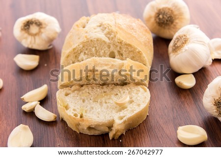 a fresh baked loaf of bread with whole cloves of roasted garlic