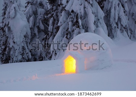 Igloo stands on the snowy lawn. Night winter mountain landscapes. House with light. Location place the Carpathian Mountains, Ukraine, Europe.