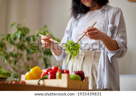 Woman is preparing vegetable salad in the kitchen, mixing leaf of salad and vegetables ina white bowl, Healthy food concept, vegan or diet. 商業照片 © 