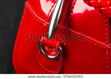 closeup of buckles, clasps, zippers, pockets, fasteners, fittings and seams on the red lacquer hand bag
