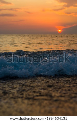 Summer sea sunset on the pebble beach, the sun, waves and clouds, beautiful dramatic lighting