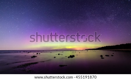 Intense northern lights (Aurora borealis) over Baltic sea. rocky beach