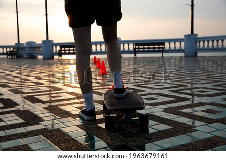Close up leg of young woman step on surf skate ready to practice at outdoor park against sun ray