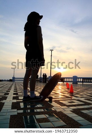 Silhouette young woman step down on surf skate board on shiny summer day . outdoor EXtream activities. Street culture