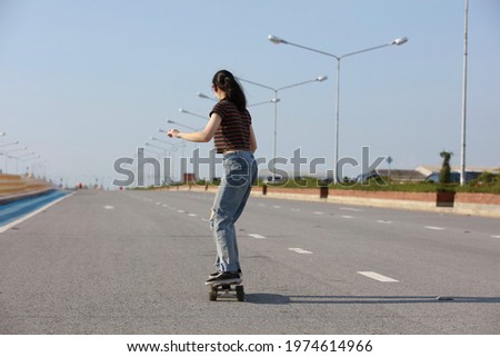 Happy and funny young woman playing surf skate board on cemen bridge along seashore, outdoor famouse sport
