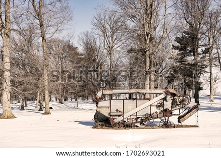 Old Rusty Piece of Farm Equipment in a Snowy Winter Landscape Sepia Tone