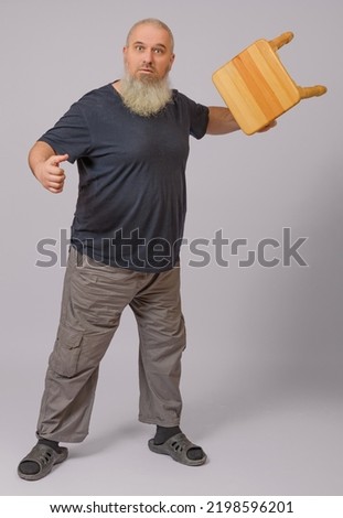 a fat man with a gray beard in home clothes and slippers swung a stool for a blow, white background Сток-фото © 