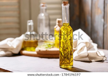 Olive oil with rosemary in glass bottles over dark wooden background. Top view, flat lay. Copy space