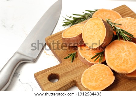 Composition of Fresh ripe sweet potatoes and rosemary spice on table against marble background