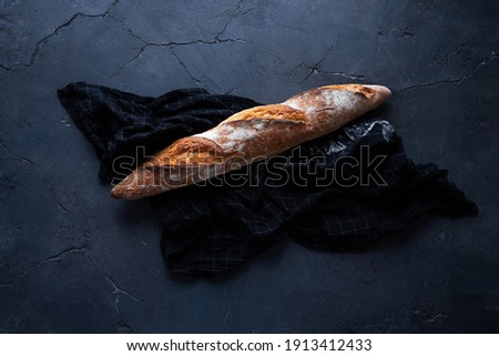 Traditional French bread baguette with napkin over a dark background. Rustic style. Top View. Flat Lay.