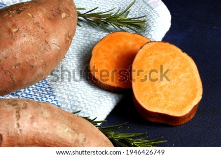Composition of sweet potatoes, rosemary spices, on a dark background. Space for text.