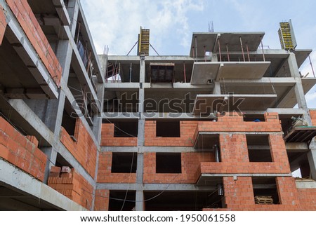 New building of a red brick multi-storey residential building. Background under construction