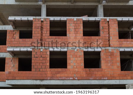 New building of a red brick multi-storey residential building. Background under construction