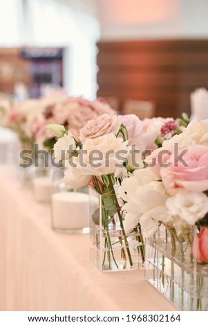 Lush floral arrangement of white and pink fresh flowers and greenery on wedding table for newlyweds. Beautiful flowers on table with white cloth, free space. Luxury wedding table decorations