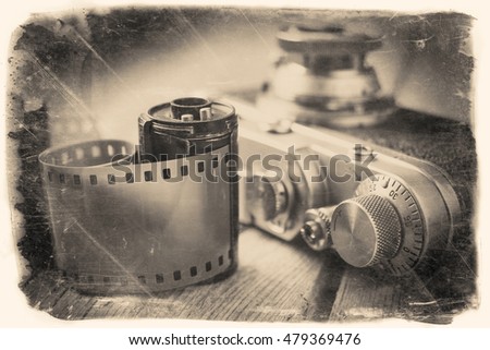 Viejo rollo de película fotográfica y cámara retro en el escritorio. Foto de estilo vintage.