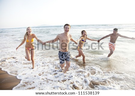 group of young people having fun, running in the surf