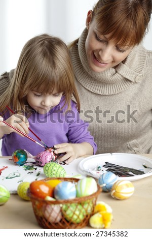 mother and daugther painting easter eggs together