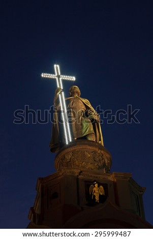 Monument of the Vladimir the Great in Kiev, Ukraine with LED light cross in the hands on the evening blue sky