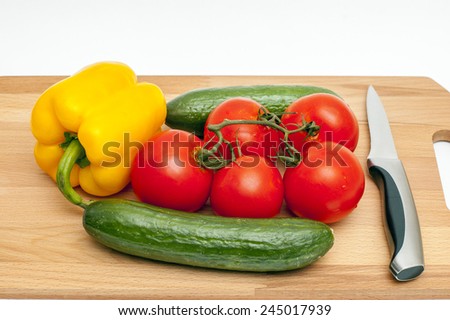 Vegetable composition: cucumbers, tomatoes and pepper on a cutting board with a knife