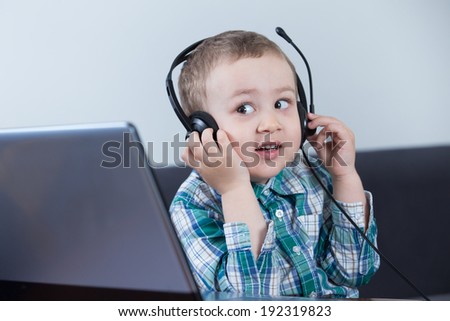 Baby boy with headphones at the computer and smiling