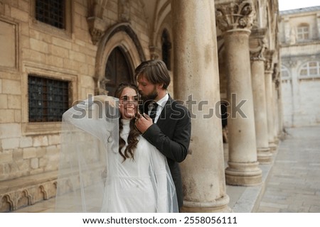 Similar – Image, Stock Photo Beautiful newlyweds hugging near the ancient door. Wedding portrait of a stylish groom and a young bride near old house in in a European town