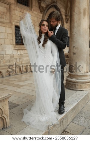 Similar – Image, Stock Photo Beautiful newlyweds hugging near the ancient door. Wedding portrait of a stylish groom and a young bride near old house in in a European town