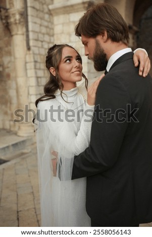 Similar – Image, Stock Photo Beautiful newlyweds hugging near the ancient door. Wedding portrait of a stylish groom and a young bride near old house in in a European town