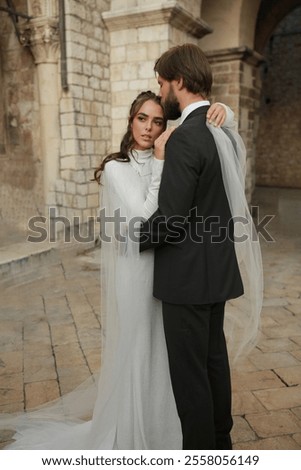 Similar – Image, Stock Photo Beautiful newlyweds hugging near the ancient door. Wedding portrait of a stylish groom and a young bride near old house in in a European town