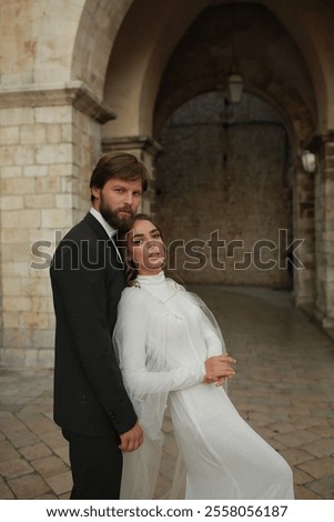 Similar – Image, Stock Photo Beautiful newlyweds hugging near the ancient door. Wedding portrait of a stylish groom and a young bride near old house in in a European town