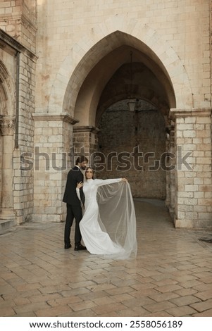 Similar – Image, Stock Photo Beautiful newlyweds hugging near the ancient door. Wedding portrait of a stylish groom and a young bride near old house in in a European town