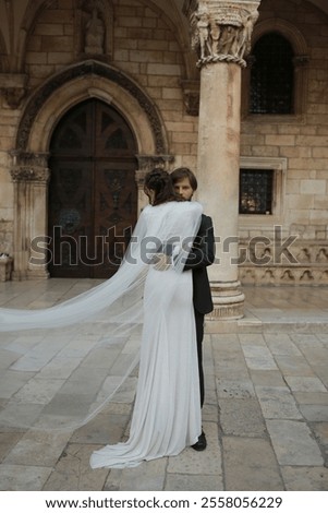 Similar – Image, Stock Photo Beautiful newlyweds hugging near the ancient door. Wedding portrait of a stylish groom and a young bride near old house in in a European town