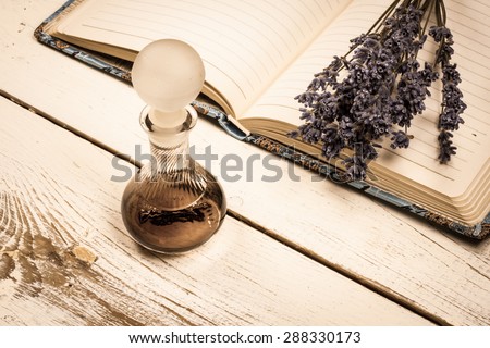 Still life vintage picture, old perfume bottle and a bunch of dried lavender on a journal.