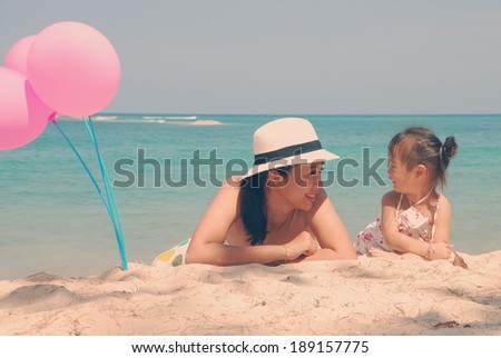 Retro style young mother and  her kid on the beach with pink balloons