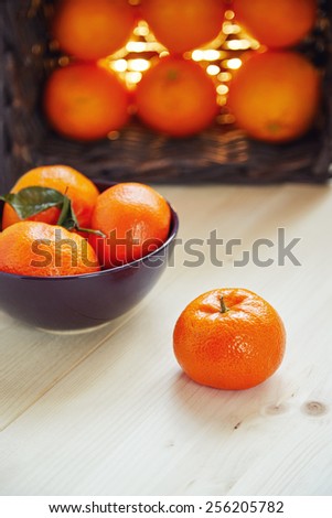 collected juicy ripe tangerines and oranges in a bowl and basket on a light wooden table
