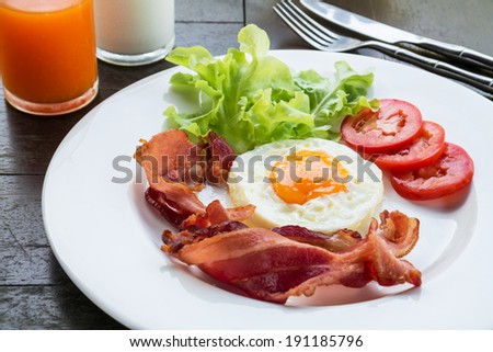 Breakfast with fried egg, bacon and vegetables on plate
