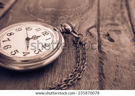 Pocket watch on wooden surface, vintage style light