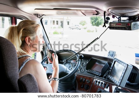 Woman truck driver in a big rig talking on the C.B. radio.