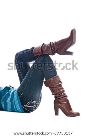 Shapely woman legs with fashion boots over denim jeans