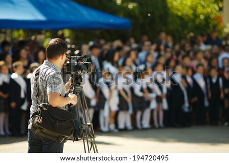 Cameraman over blurry background, primary school event graduation.
