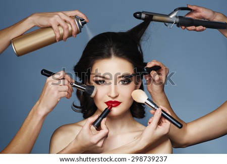 Many hands with cosmetics brush, shadows doing make up of glamour asian girl